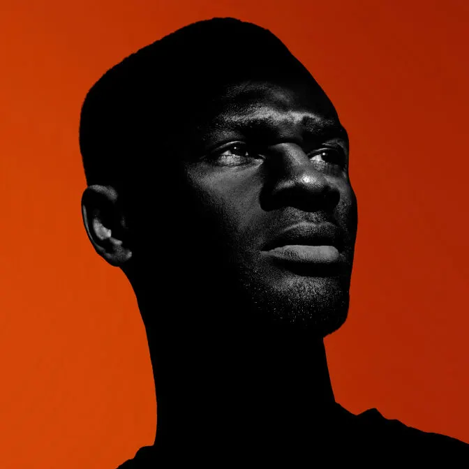 Side-lit profile portrait of a colleague against a deep red backdrop
