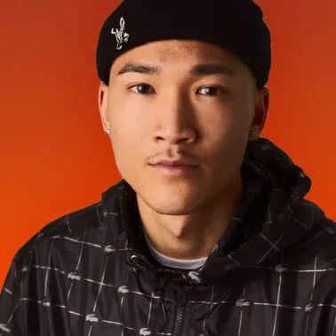 Studio portrait of a colleague in a black beanie on an orange backdrop