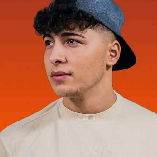 Studio portrait of a colleague in a cap looking off camera on orange