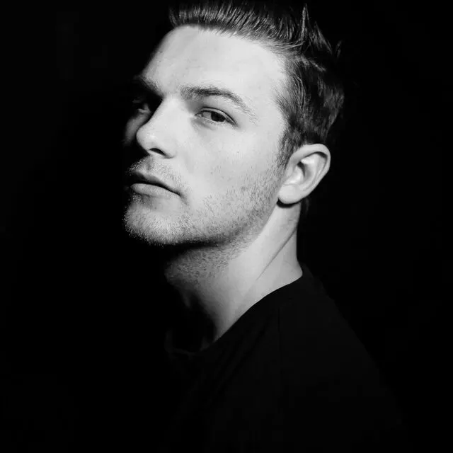 Black and white portrait of a colleague in a dark t-shirt against a black background