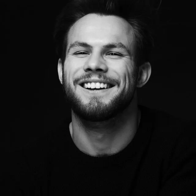 Black and white portrait of a smiling colleague in a dark sweater